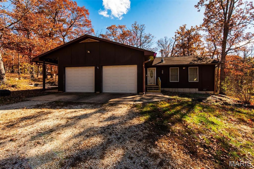 Ranch-style house featuring dirt driveway, a garage, and board and batten siding