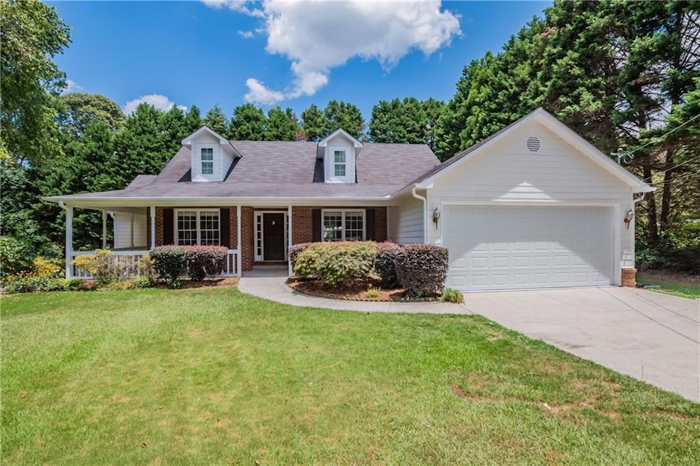 View of front of home featuring brick siding, driveway, a garage, a front yard, and a porch
