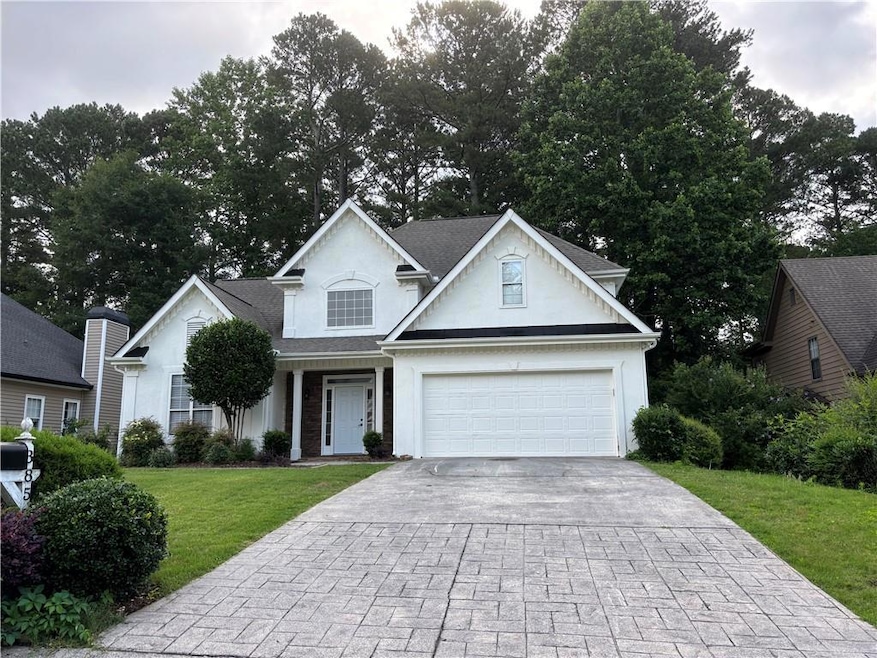 Traditional-style house with driveway, a front yard, and stucco siding