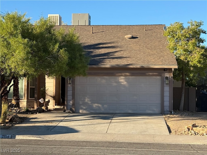 View of front facade featuring concrete driveway, a garage, and roof with shingles