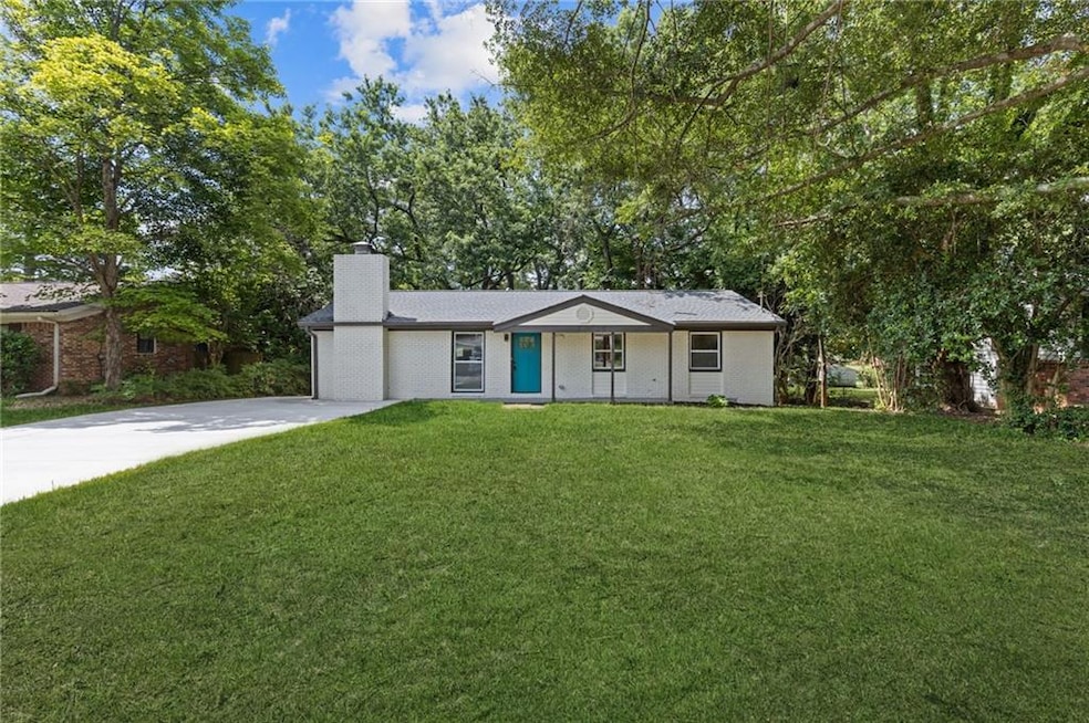View of front facade featuring concrete driveway, a front lawn, and a chimney