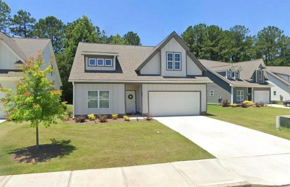View of front of house featuring board and batten siding, concrete driveway, a front lawn, and roof with shingles