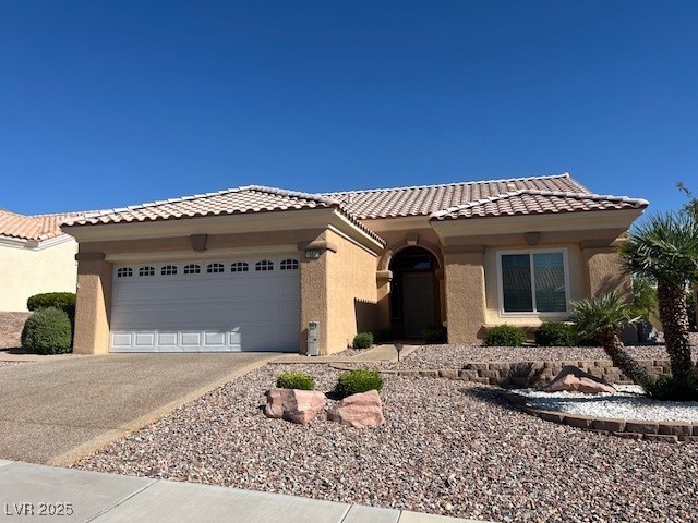 View of front facade with an attached garage, stucco siding, driveway, and a tile roof