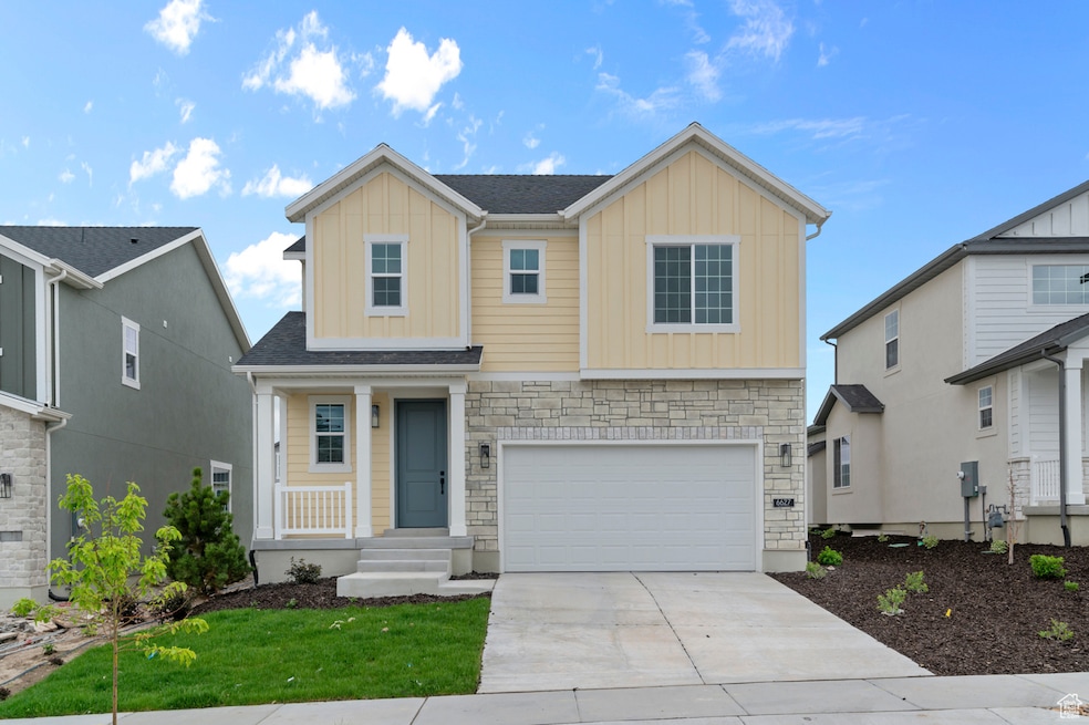 View of front of home featuring board and batten siding, a garage, concrete driveway, stone siding, and a front yard