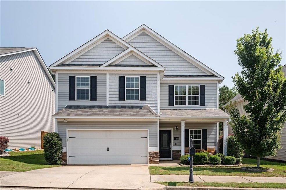 Craftsman house featuring concrete driveway, an attached garage, covered porch, a shingled roof, and a front yard