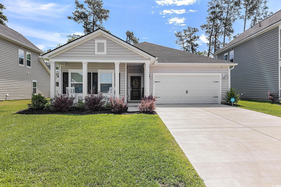 View of front of property with a garage, a front yard, driveway, and covered porch