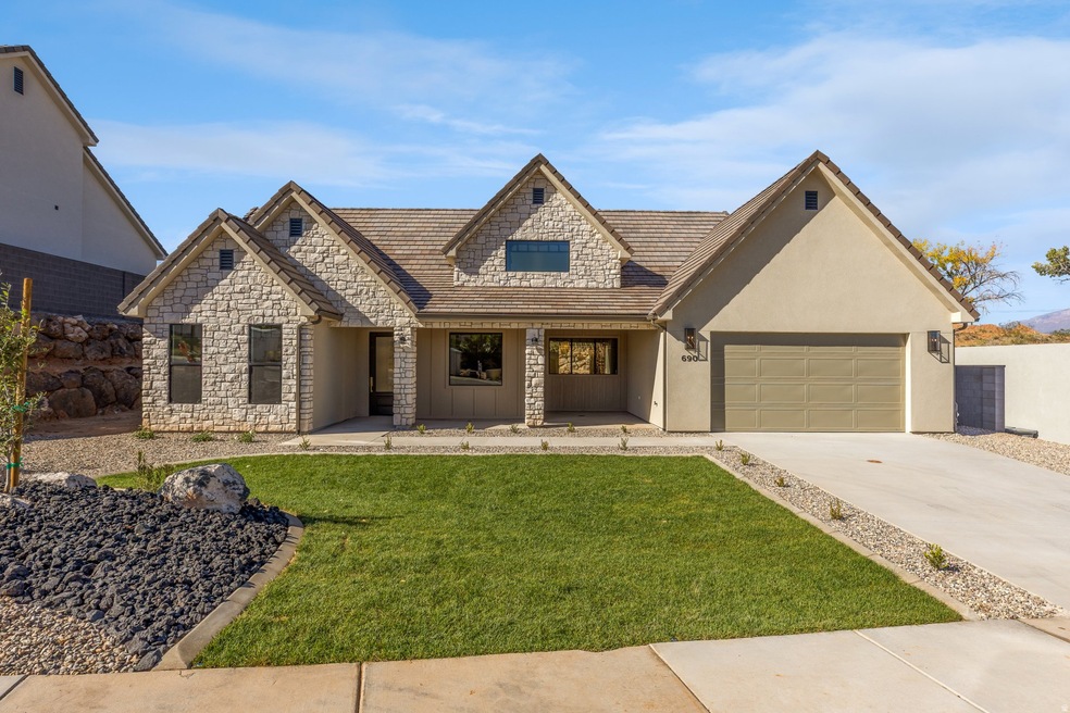 View of front facade with covered porch, concrete driveway, stone siding, stucco siding, and an attached garage