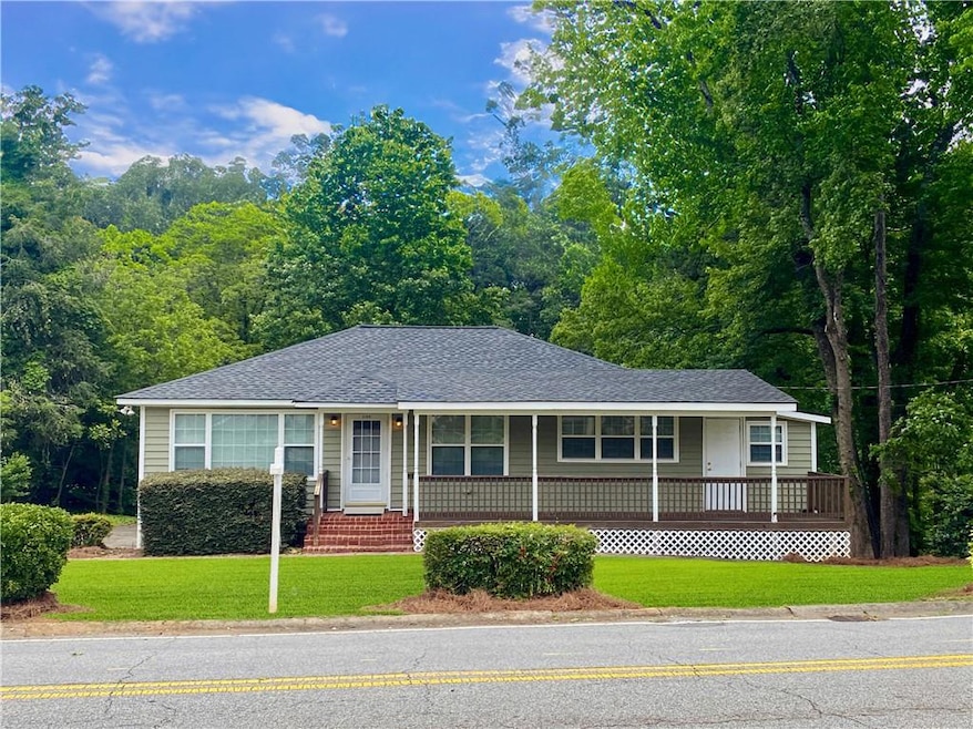 Ranch-style house featuring covered porch, a front yard, and a shingled roof