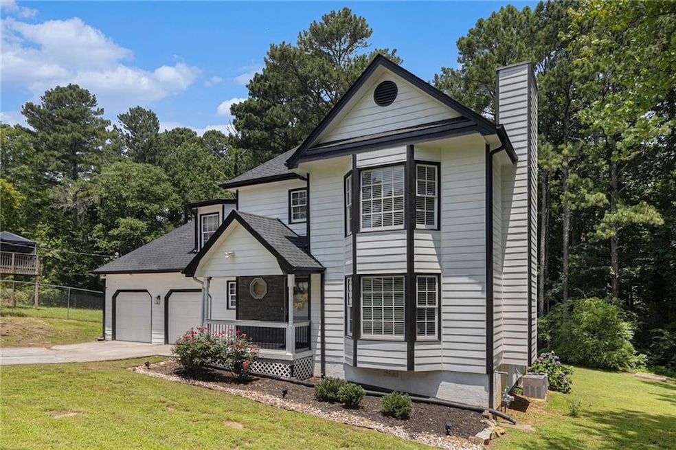 Traditional-style home with a chimney, a garage, concrete driveway, and a shingled roof