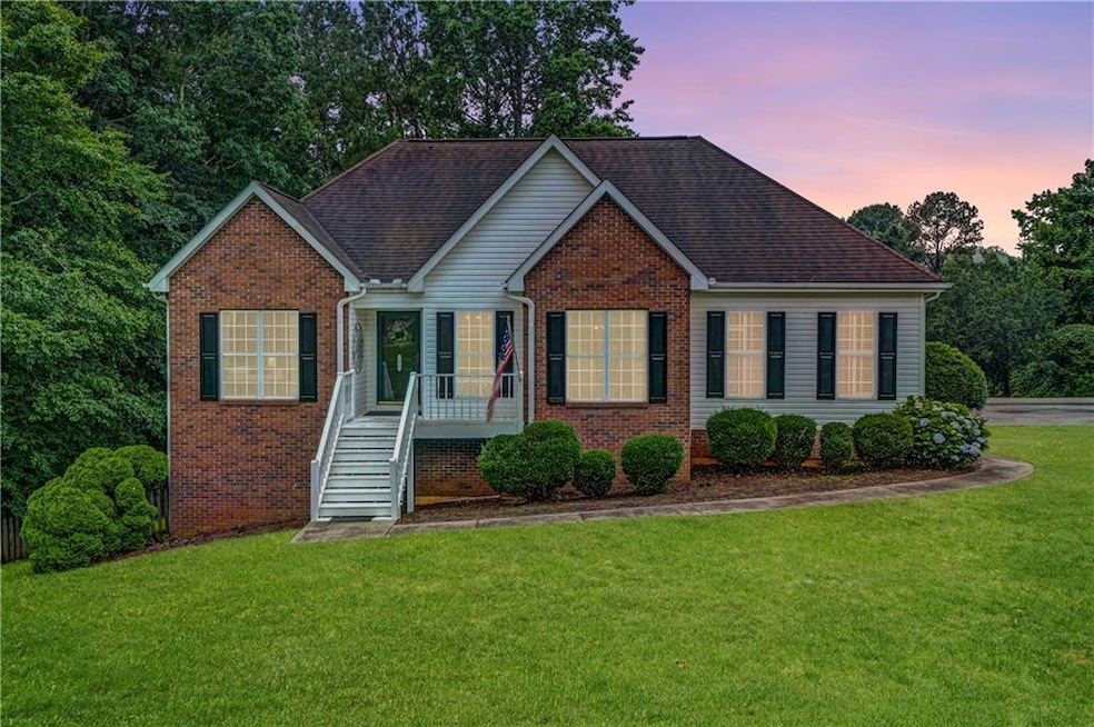 View of front facade with brick siding, a yard, and roof with shingles