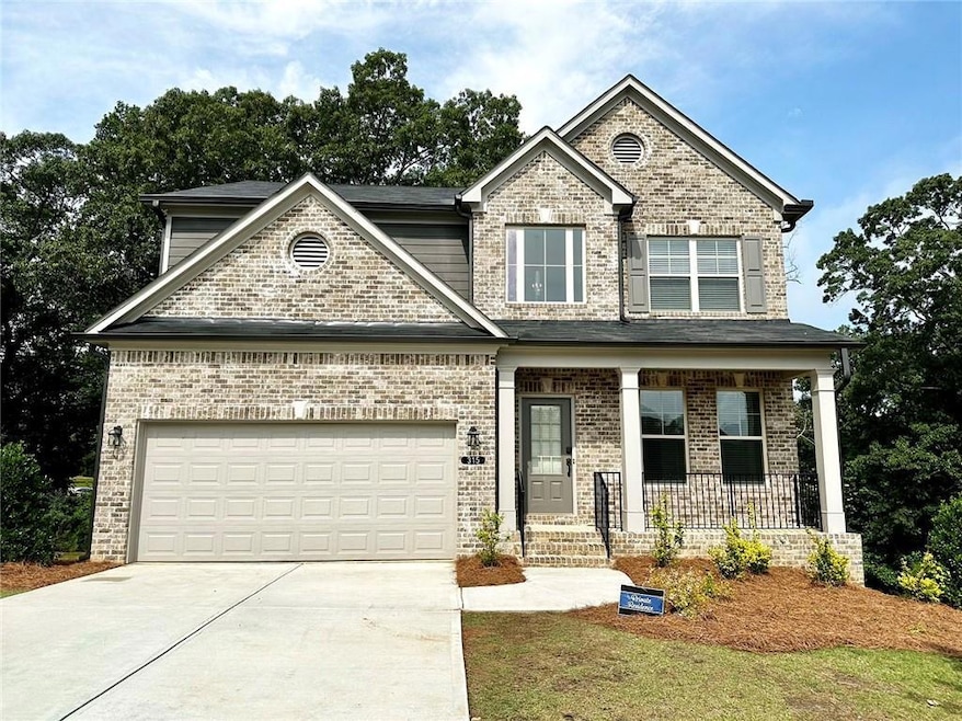 View of front of home with covered porch, concrete driveway, brick siding, and a garage