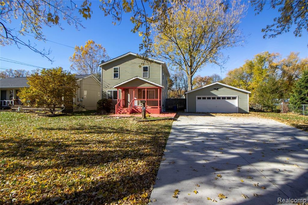 View of front of property with an outbuilding, a detached garage, and a sunroom