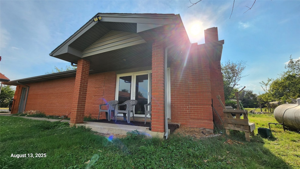 View of side of home featuring a yard, brick siding, and a chimney