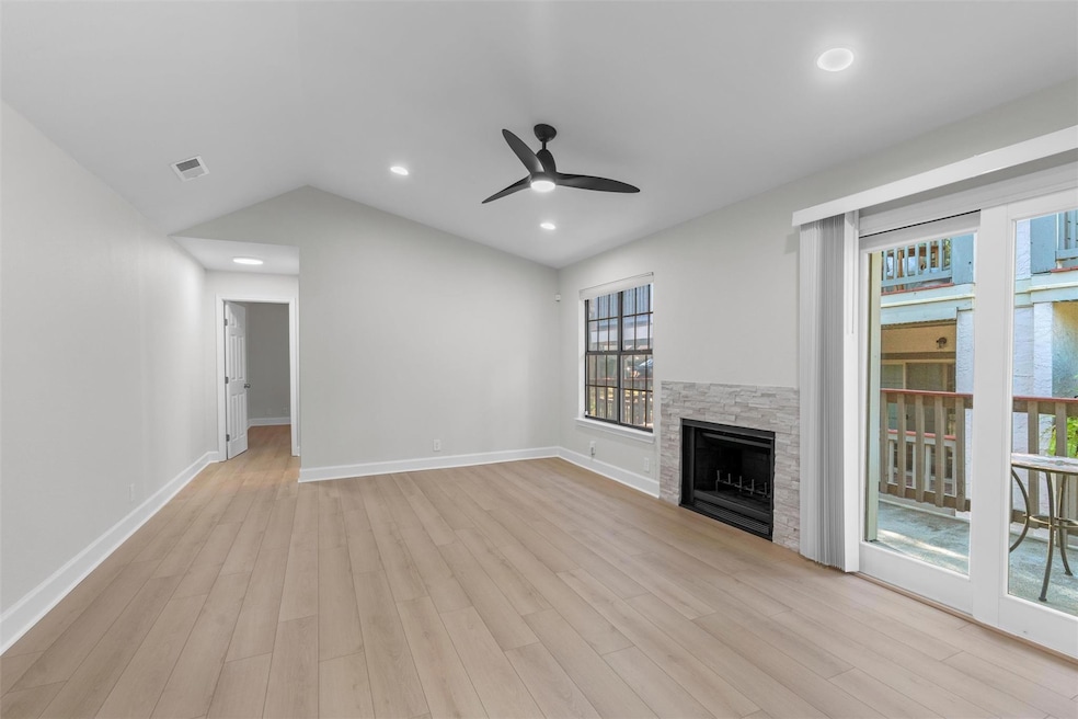 Unfurnished living room with vaulted ceiling, a ceiling fan, a fireplace, light wood-style flooring, and recessed lighting