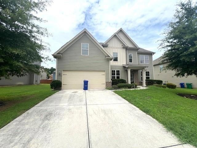 View of front of house featuring board and batten siding, driveway, an attached garage, and a front lawn