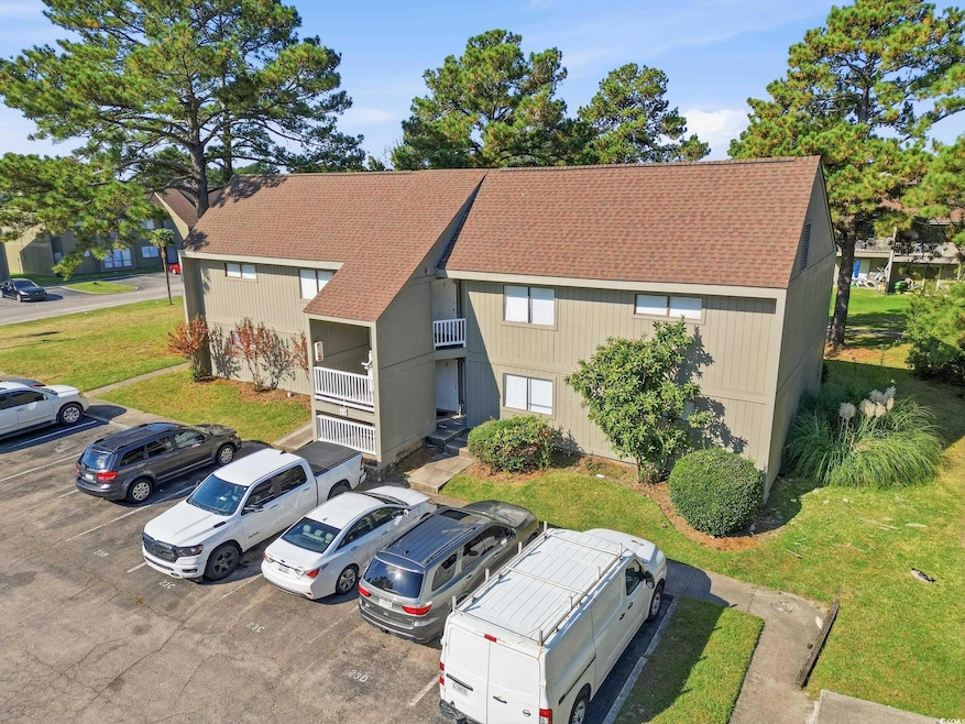 View of front facade with roof with shingles, uncovered parking, and a front yard