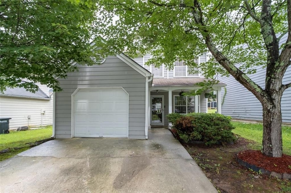 View of front of property featuring an attached garage, concrete driveway, and a porch
