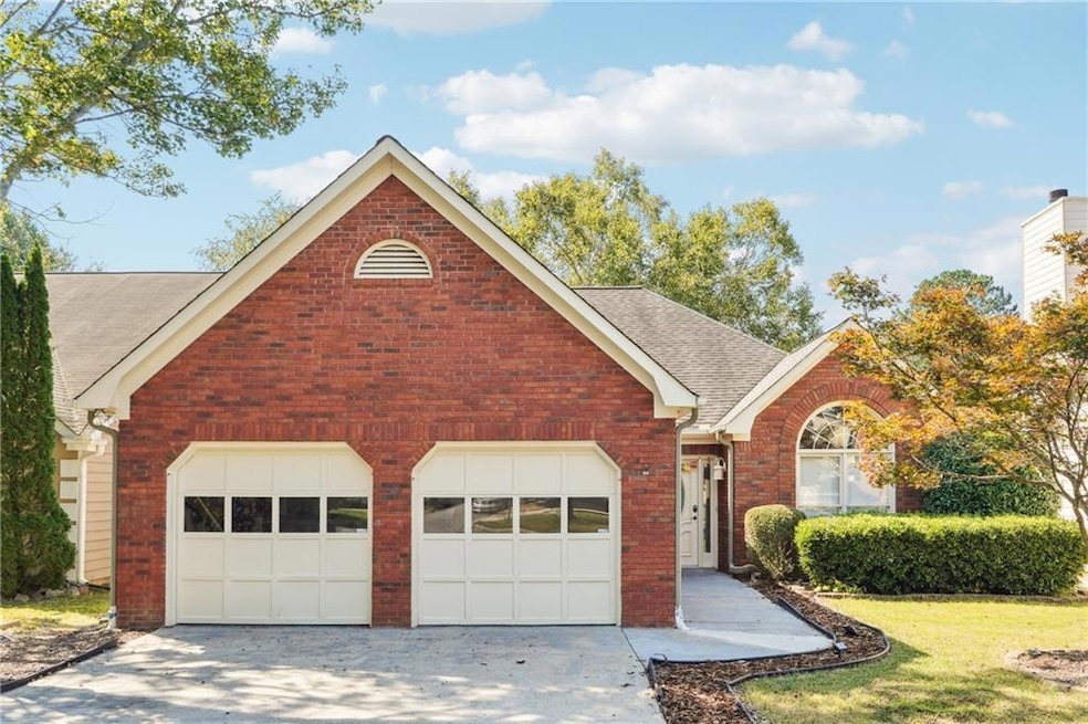 View of front of house featuring a shingled roof, brick siding, driveway, a front yard, and an attached garage