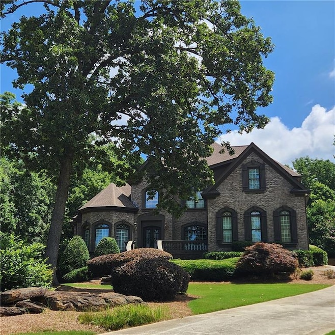 French provincial home featuring a front lawn and brick siding