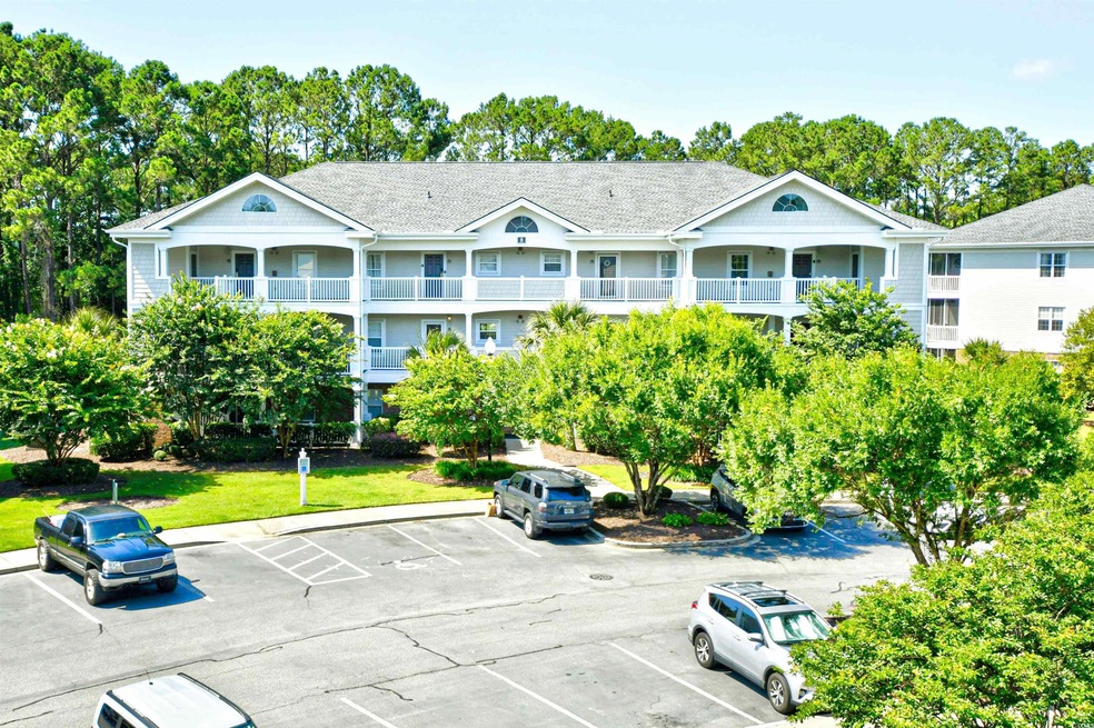 View of property featuring uncovered parking and view of wooded area