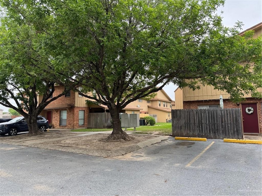 View of front of Las Torres Condo Units featuring brick siding, fence, and uncovered parking