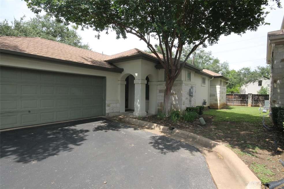 Single story home featuring stone siding, asphalt