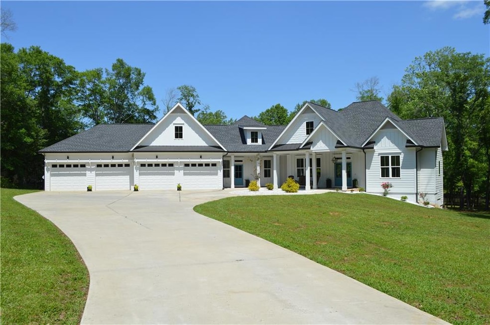 Modern farmhouse style home with a front yard, covered porch, concrete driveway, and roof with shingles
