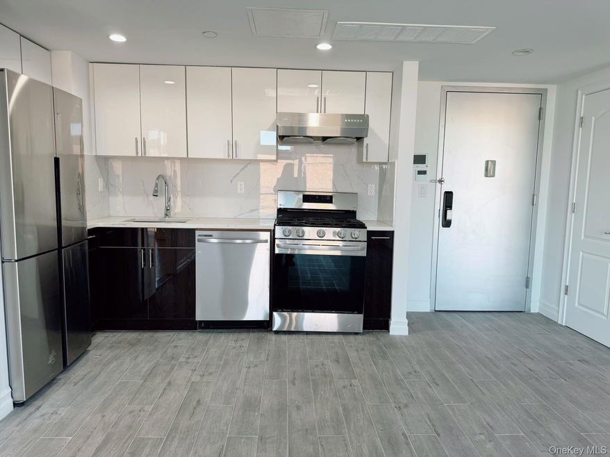 Kitchen featuring a sink, tasteful backsplash, under cabinet range hood, stainless steel appliances, and visible vents