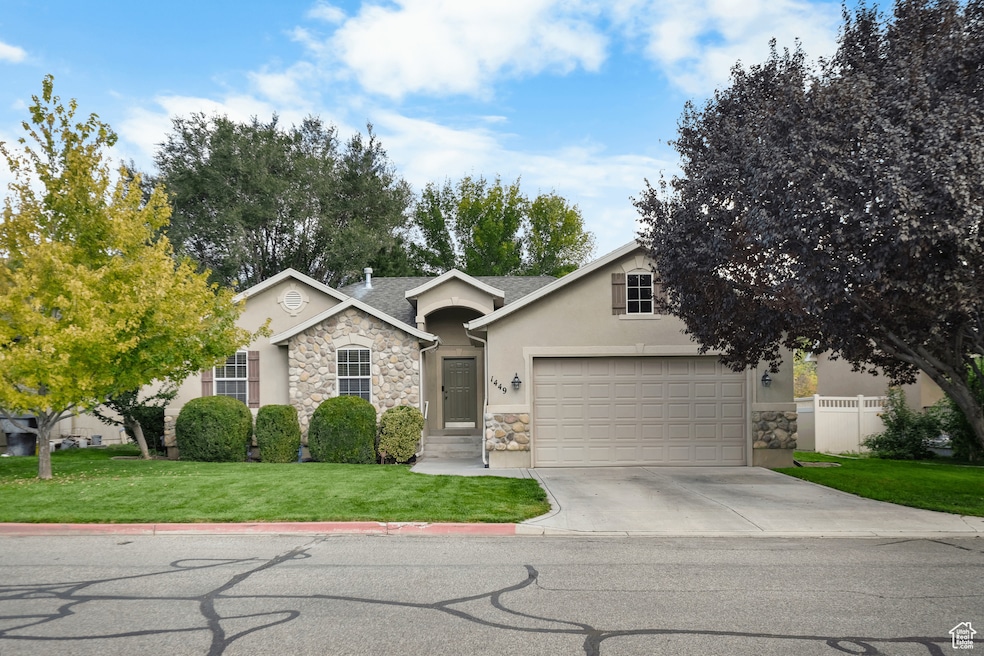 Ranch-style house with stone siding, stucco siding, a front yard, driveway, and roof with shingles