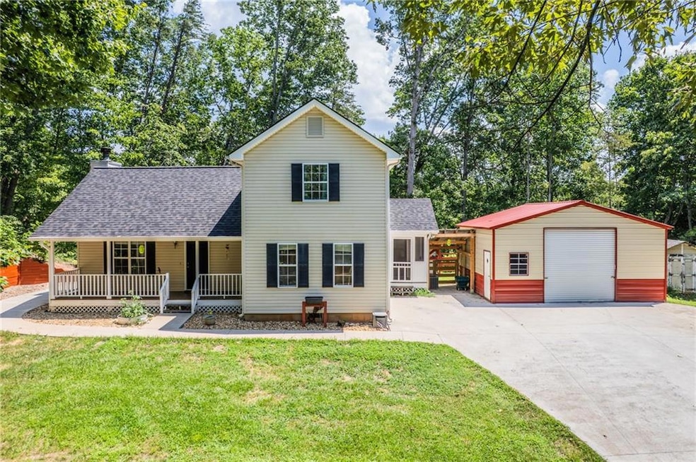 Traditional-style house with a porch, roof with shingles, an outdoor structure, and a front lawn