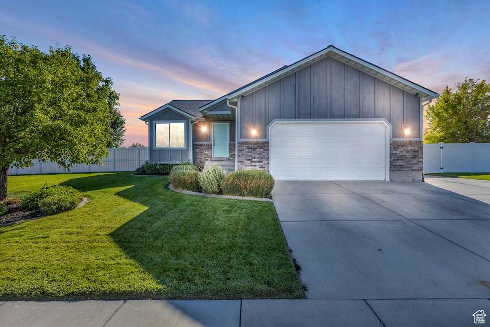 Single story home with board and batten siding, an attached garage, driveway, and brick siding