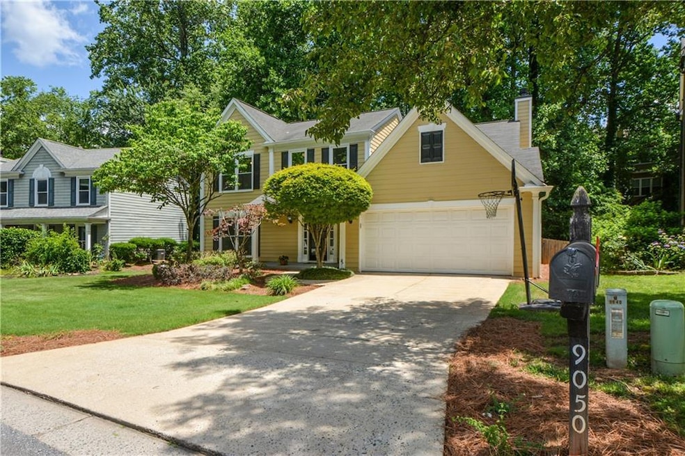 View of front of property with concrete driveway, a front lawn, a chimney, and a garage