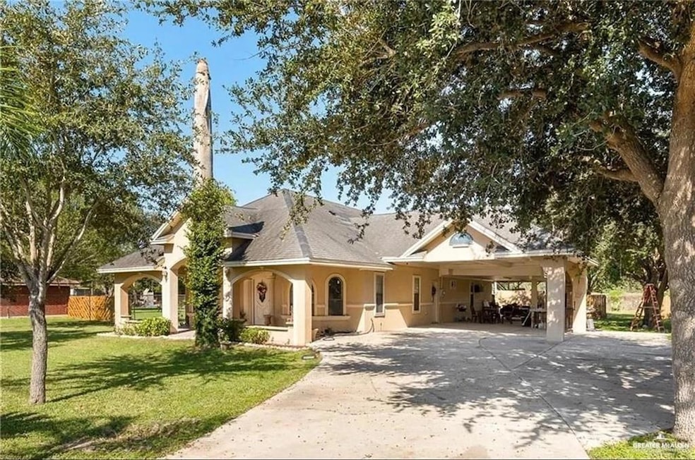 View of front of house featuring driveway, a front yard, a carport, and stucco siding