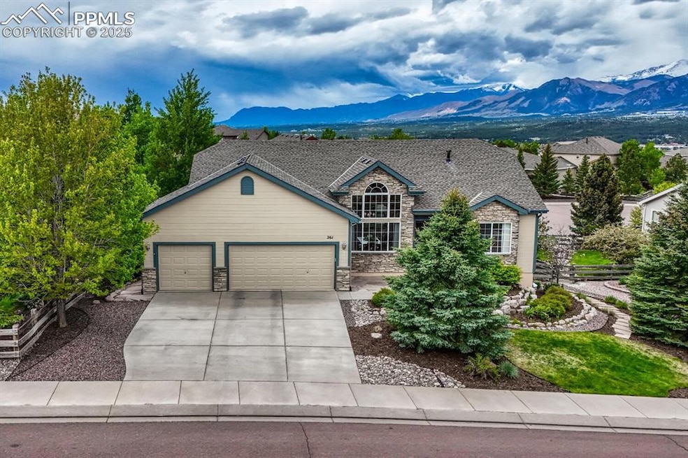 View of front of home with a mountain view, stone siding, a garage, and driveway