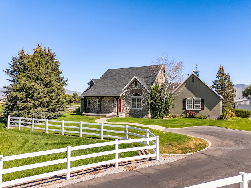 View of front of house with covered porch, a fenced front yard, a shingled roof, and stone siding