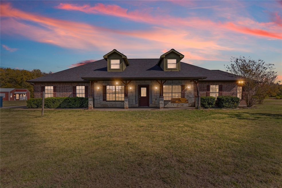 View of front of property with a porch, a front lawn, brick siding, and roof with shingles