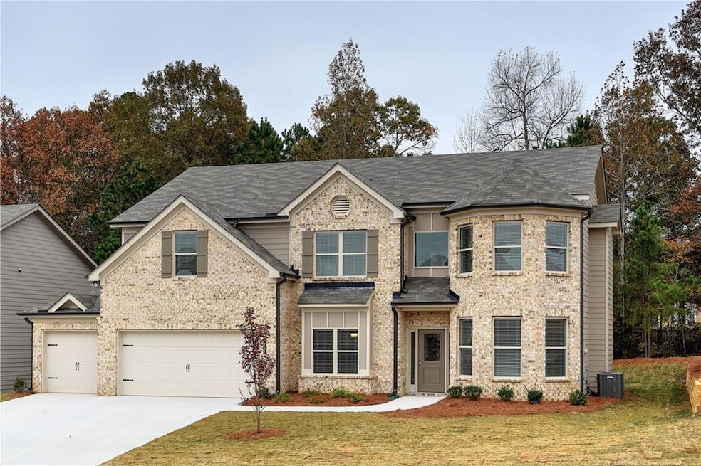 View of front of home with a front yard, central air condition unit, and a garage