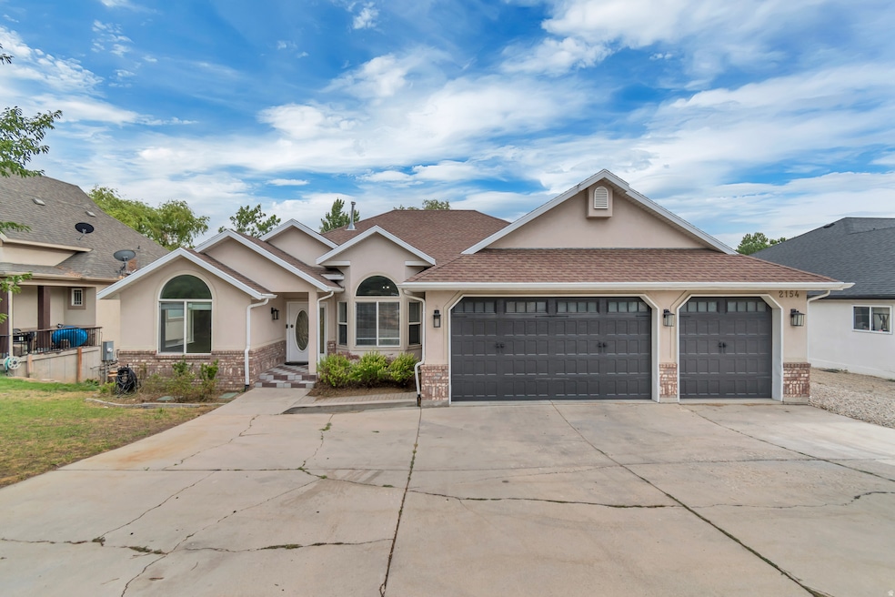 View of front of home with stucco siding, concrete driveway, a garage, and roof with shingles
