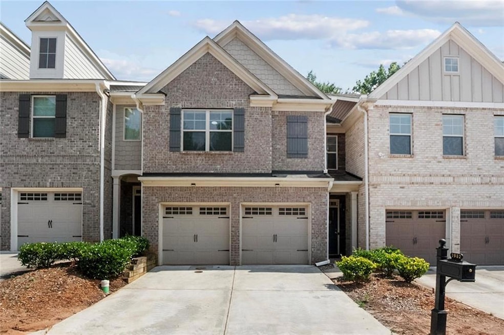 Townhome / multi-family property with driveway, a garage, brick siding, and board and batten siding