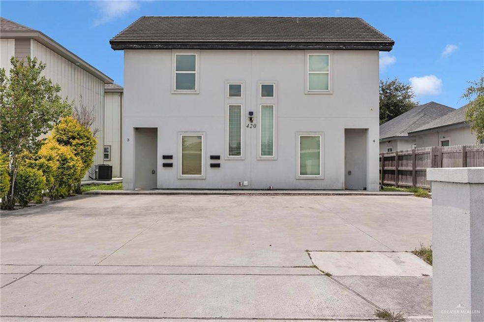 View of front facade featuring stucco siding, driveway, a tile roof, and a patio