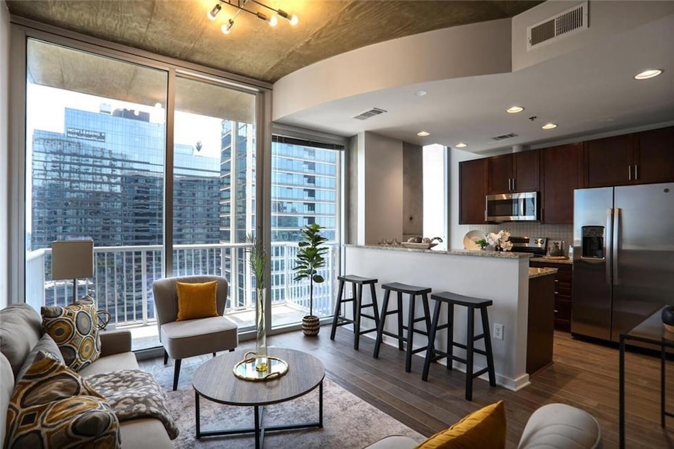 Living room with expansive windows, dark wood finished floors, and recessed lighting