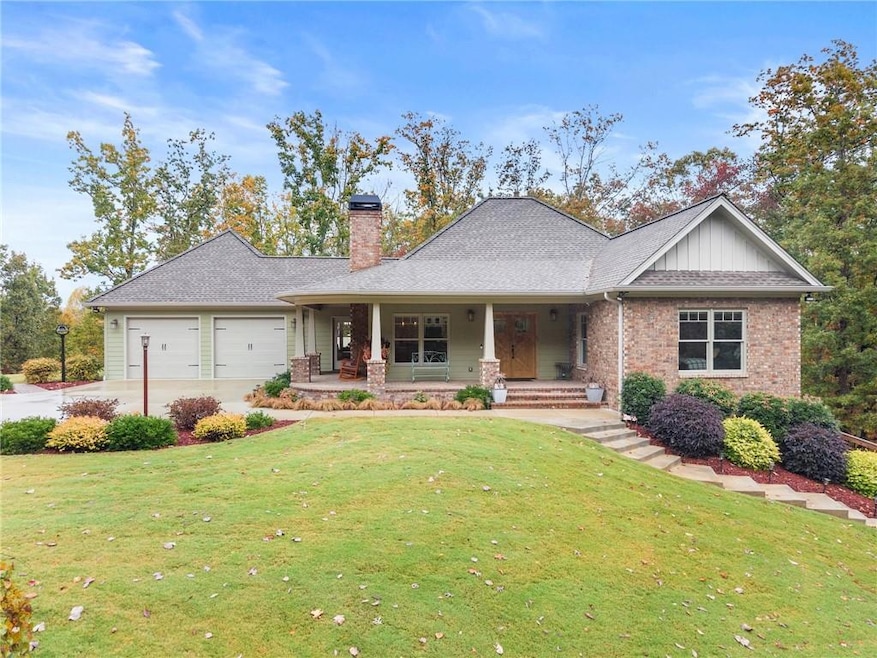View of front of property featuring a porch, a front yard, a chimney, brick siding, and a shingled roof