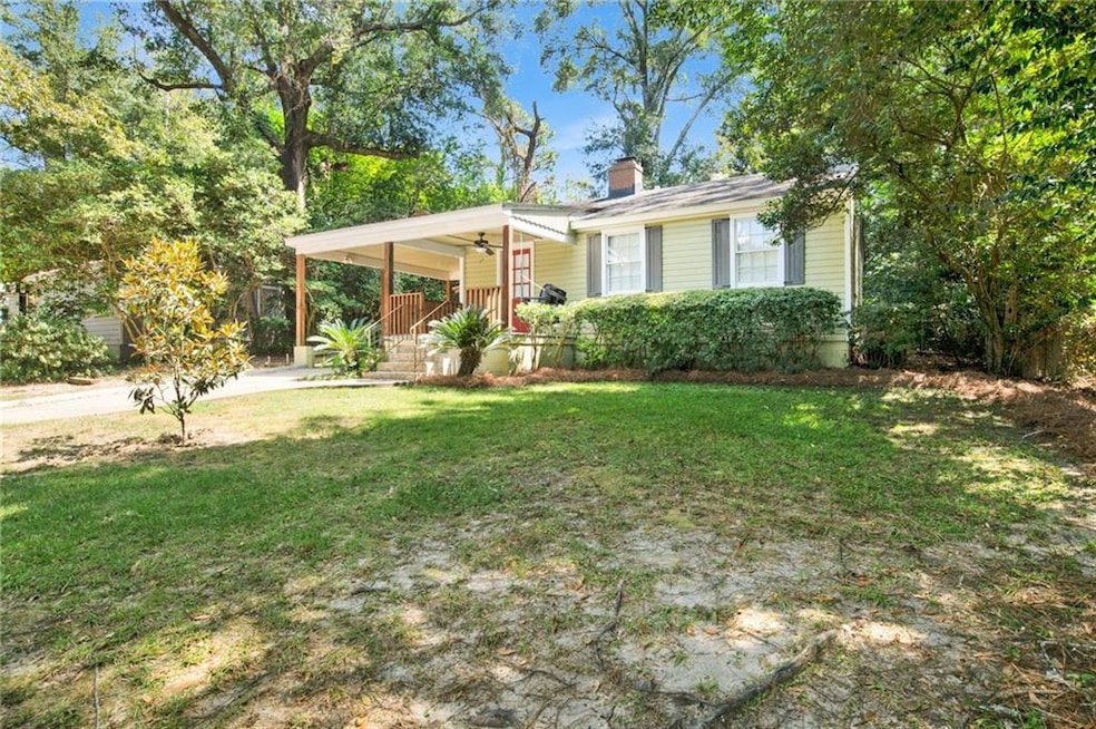 View of front of house featuring a front lawn, an attached carport, a chimney, a porch, and driveway