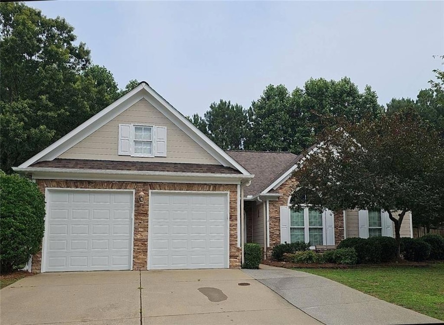 View of front of house with roof with shingles, a garage, brick siding, and driveway