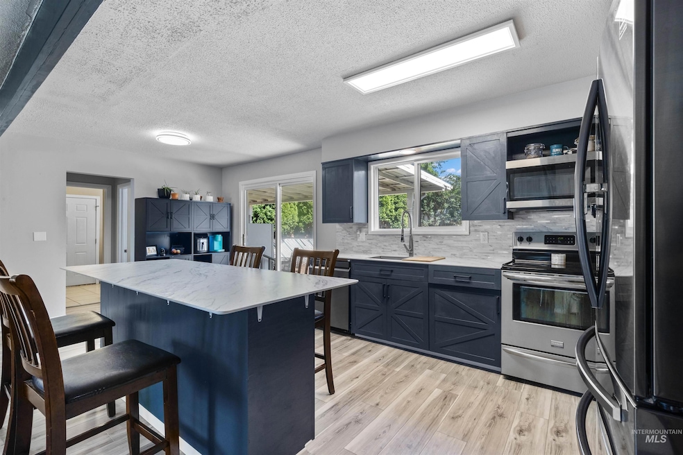 Kitchen featuring stainless steel appliances, a kitchen breakfast bar, light wood finished floors, tasteful backsplash, and a textured ceiling
