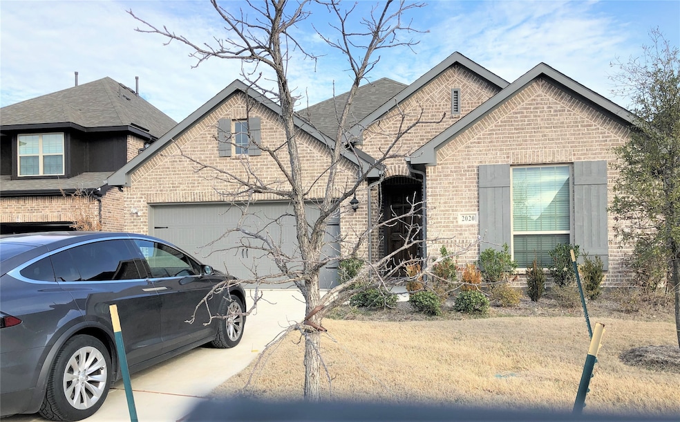 French country home with brick siding, driveway, roof with shingles, and a garage