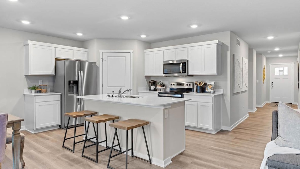 Modern kitchen with stainless steel appliances and microwave venting outside. Model home, finishes will vary.