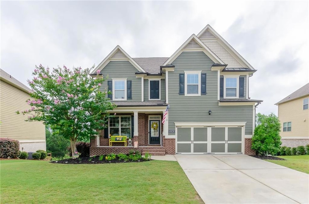 Craftsman inspired home with a porch, a front yard, brick siding, concrete driveway, and a garage