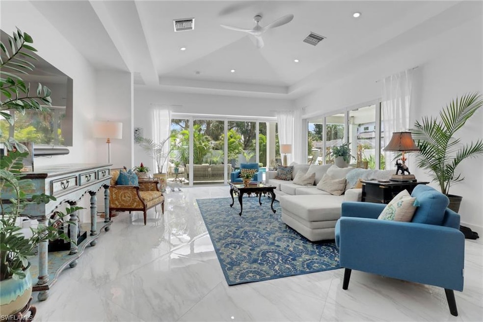 Living room featuring a tray ceiling, ceiling fan, marble tiled flooring, and recessed lighting