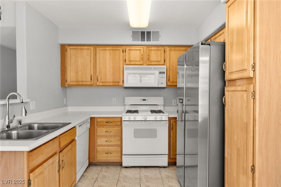 Kitchen featuring white appliances, light countert